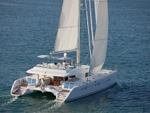 Jyohana Lagoon 620 sailing catamaran underway with sails up and guests relaxing on flybridge and aft deck at sea