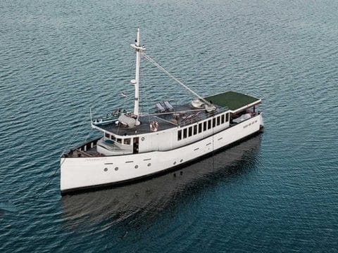 Splendour classic white luxury motor yacht aerial view with dark superstructure and single mast on deep blue Indonesian waters