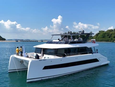 Side view of Oceanwalker 60 luxury motor yacht with crew on deck cruising near Singapore